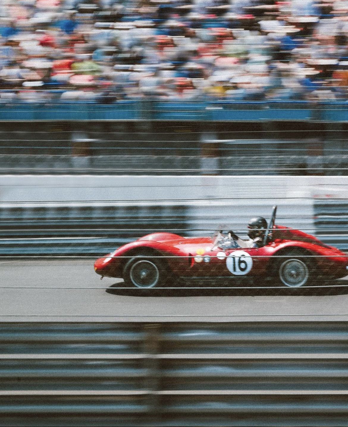 Red race car with number 16 on a track, blurred motion effect